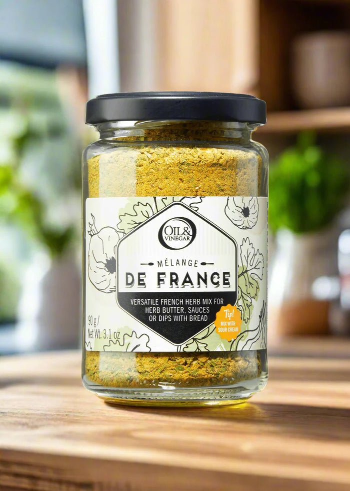 Jar of 'Melange De France' herb mix on a wooden surface with a blurred kitchen background