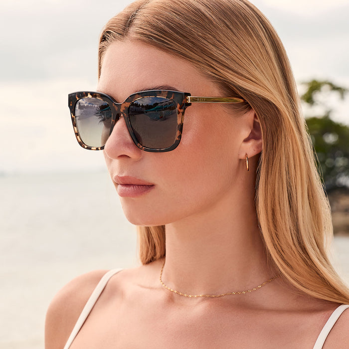 lifestyle - female outdoors wearing bella square oversized sunglasses with a espresso tortoise frame and grey gradient polarized lenses angled view