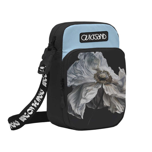 The Quicksand small psychic bag comes in black and light blue with a large white flower print on the front pocket, a QUICKSAND logo patch, and a black strap featuring white repeating text.