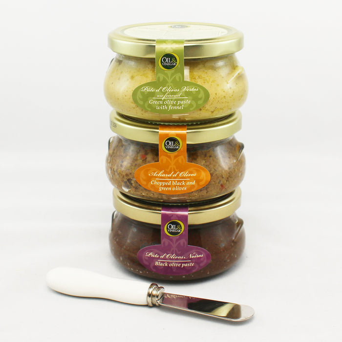 three jars of tapenades stack on top of each other with gold lids and labels indicating the flavors