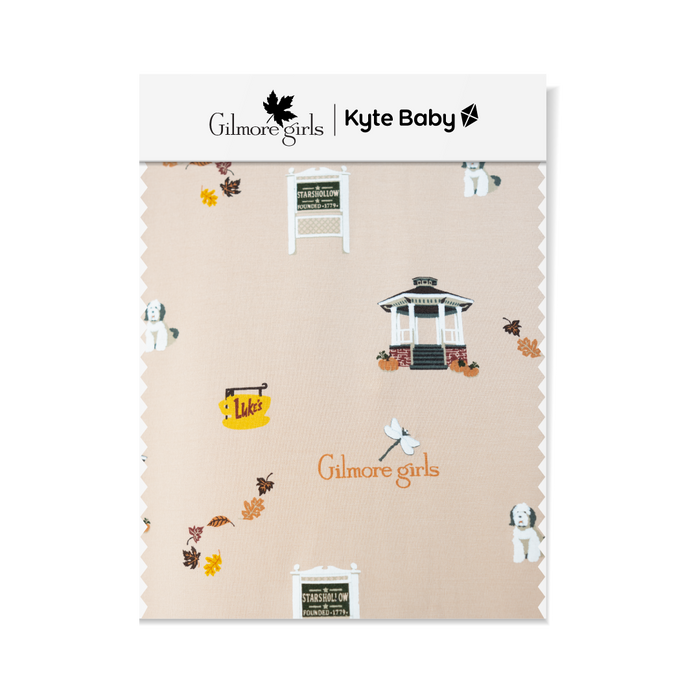GIlmore Girls Fabric swatch featuring Stars Hallow sign, gazebo, Lukes coffee sign, fall leaves, Gilmore Girls logo and a white and grey dog.
