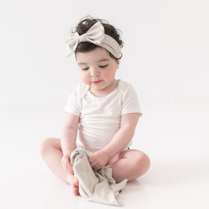 Baby wearing Bow Headband in Oat while holding Kite Lovey