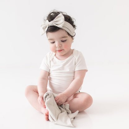 Baby wearing Bow Headband in Oat while holding Kite Lovey