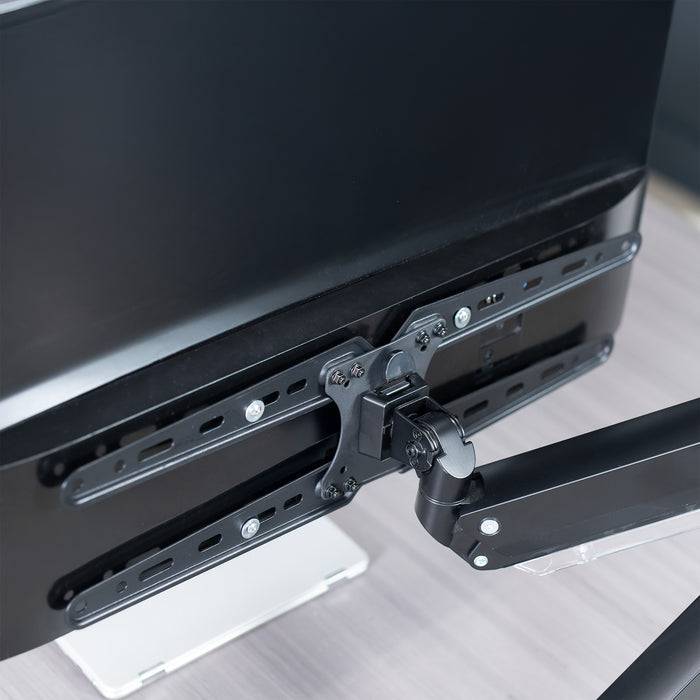 Black monitor arm with VESA Extension Brackets attached to a computer monitor on a desk
