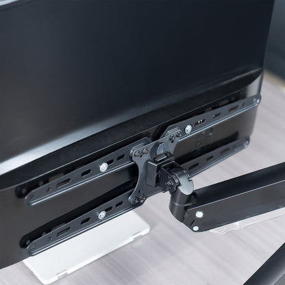Black monitor arm with VESA Extension Brackets attached to a computer monitor on a desk