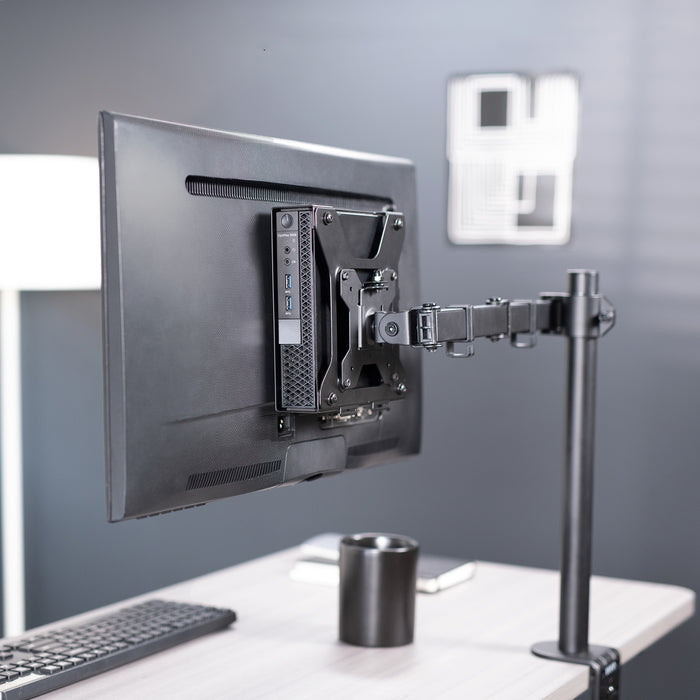 Monitor mounted on a flexible arm stand with a Mount Designed for Dell OptiPlex Micro and a keyboard and cup on a desk.