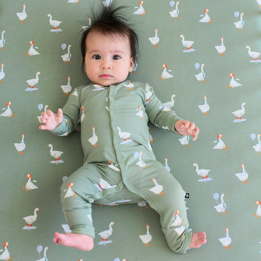 Infant laying in a crib on a Silly Goose Crib Sheet wearing matching snap Romper pajamas