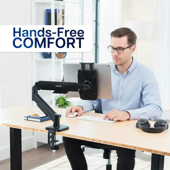 Man using a tablet with a monitor stand labeled 'Hands-Free Comfort' in an office setting.