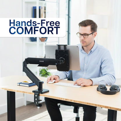 Man using a tablet with a monitor stand labeled 'Hands-Free Comfort' in an office setting.