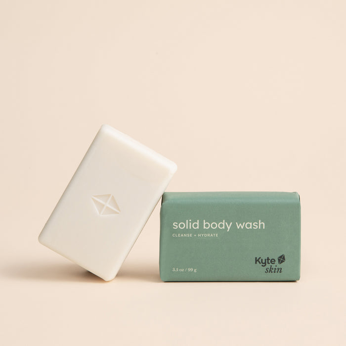 Two bars of solid body wash, one white and one green, with 'Kyte Skin' branding on a beige background.