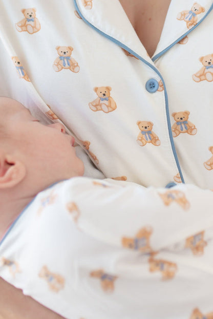 Woman wearing teddy bear patterned pajamas holding a baby in same print pajamas